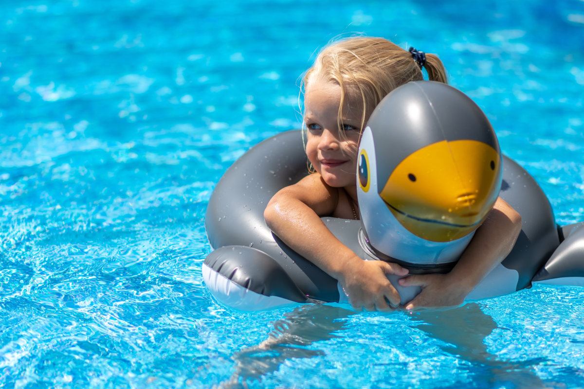 Mädchen badet im Pool mit einem aufblasbaren Schwimmring.